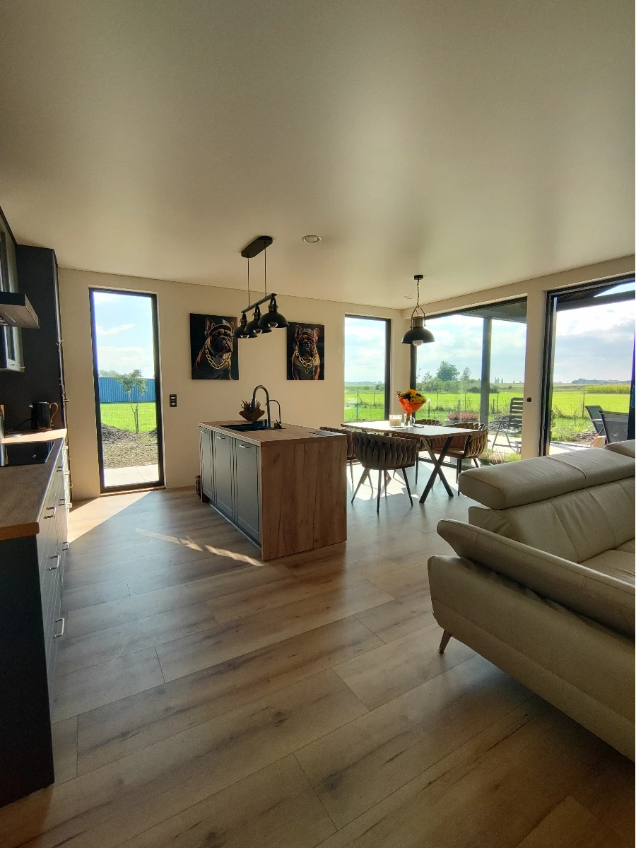 Przestronny salon z aneksem kuchennym i jadalnią w domu kontenerowym całorocznym, duże okna na zieleń